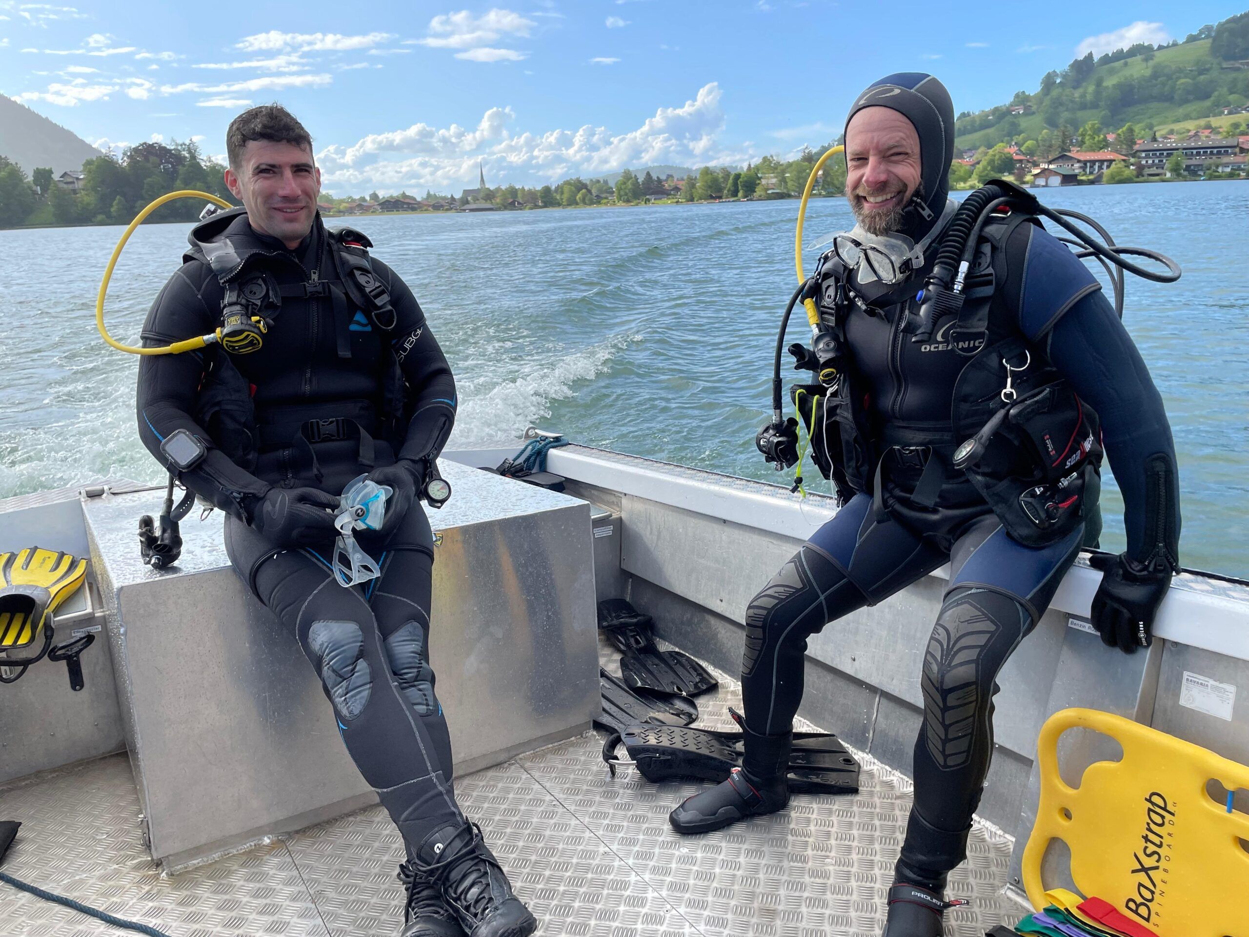 Zwei Taucher sitzen nach einem Tauchgang auf dem Rettungsboot der Wasserwacht Schliersee